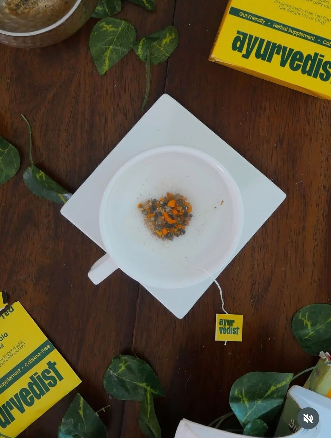 An Ayurvedist Be Aligned tea sachet on a white dish beside the yellow box on a dark wood table